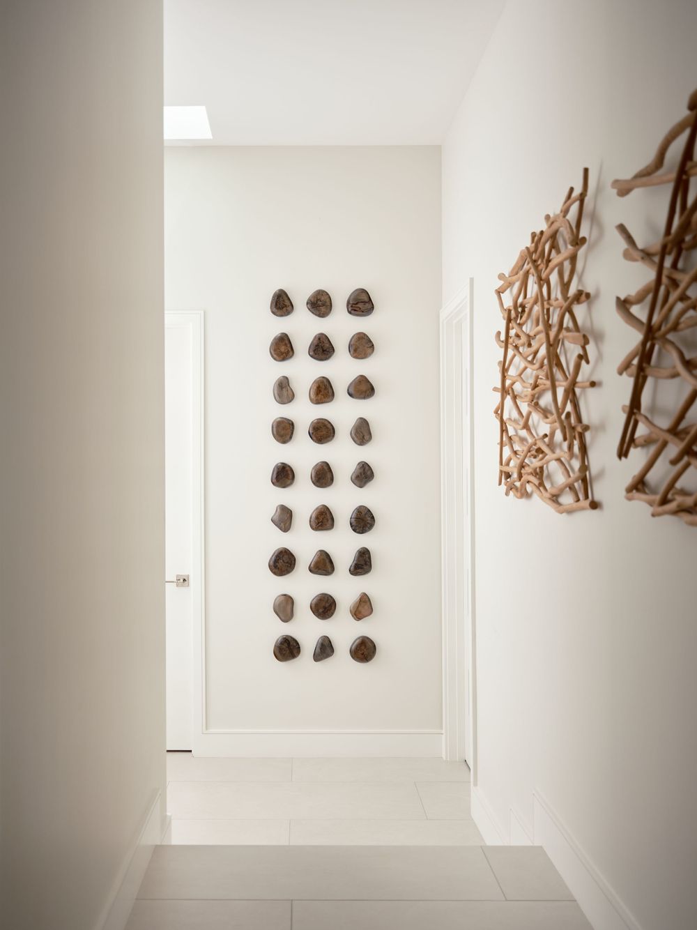 Sculptural hallway with modern art installations and soft white tones — Alta La Jolla project by Khoi Ly Photography.