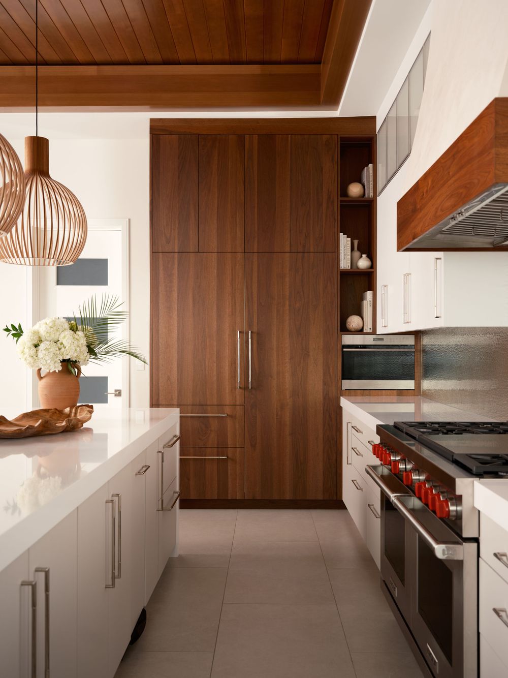 High-end kitchen with white cabinets, pendant lights, and wood ceiling — luxury interior design by Khoi Ly.
