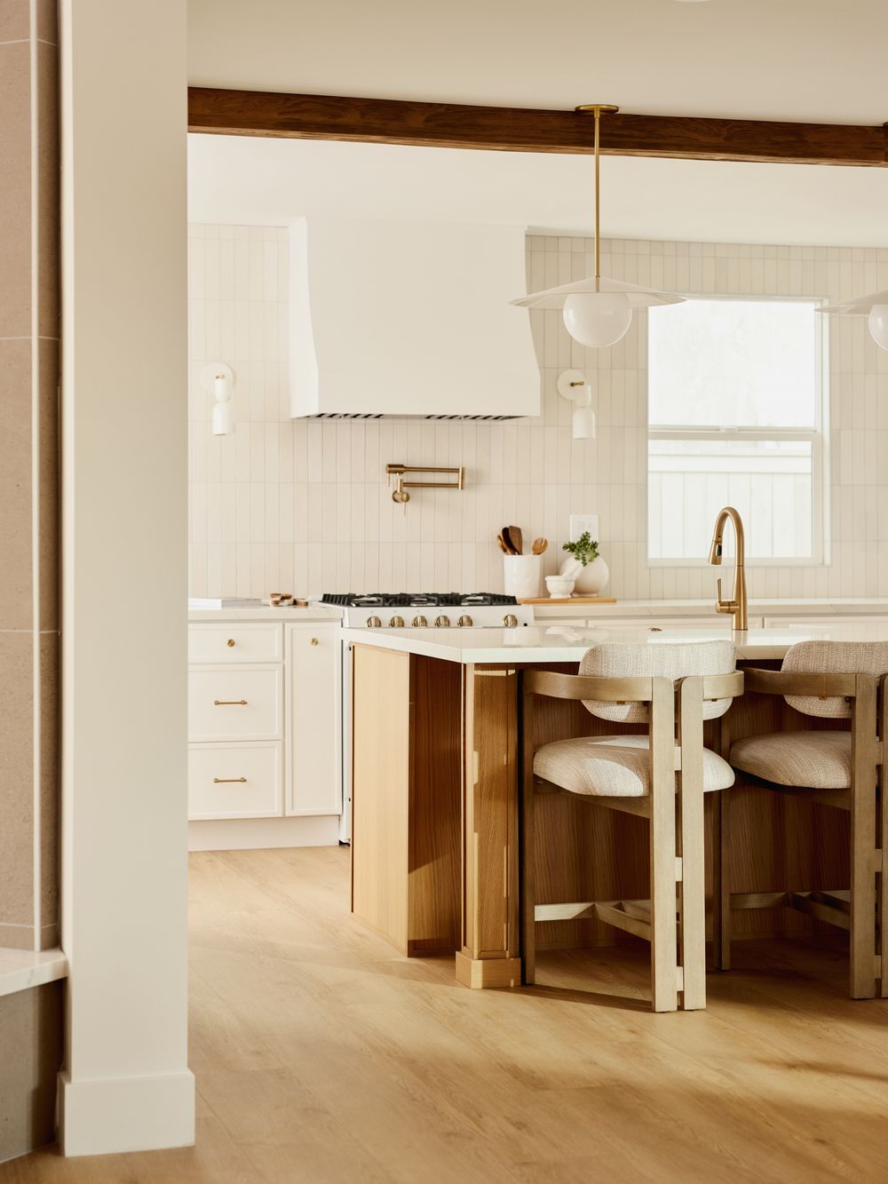 Bright kitchen with shaker cabinets, marble backsplash, and soft wood flooring — interior design captured by Khoi Ly.