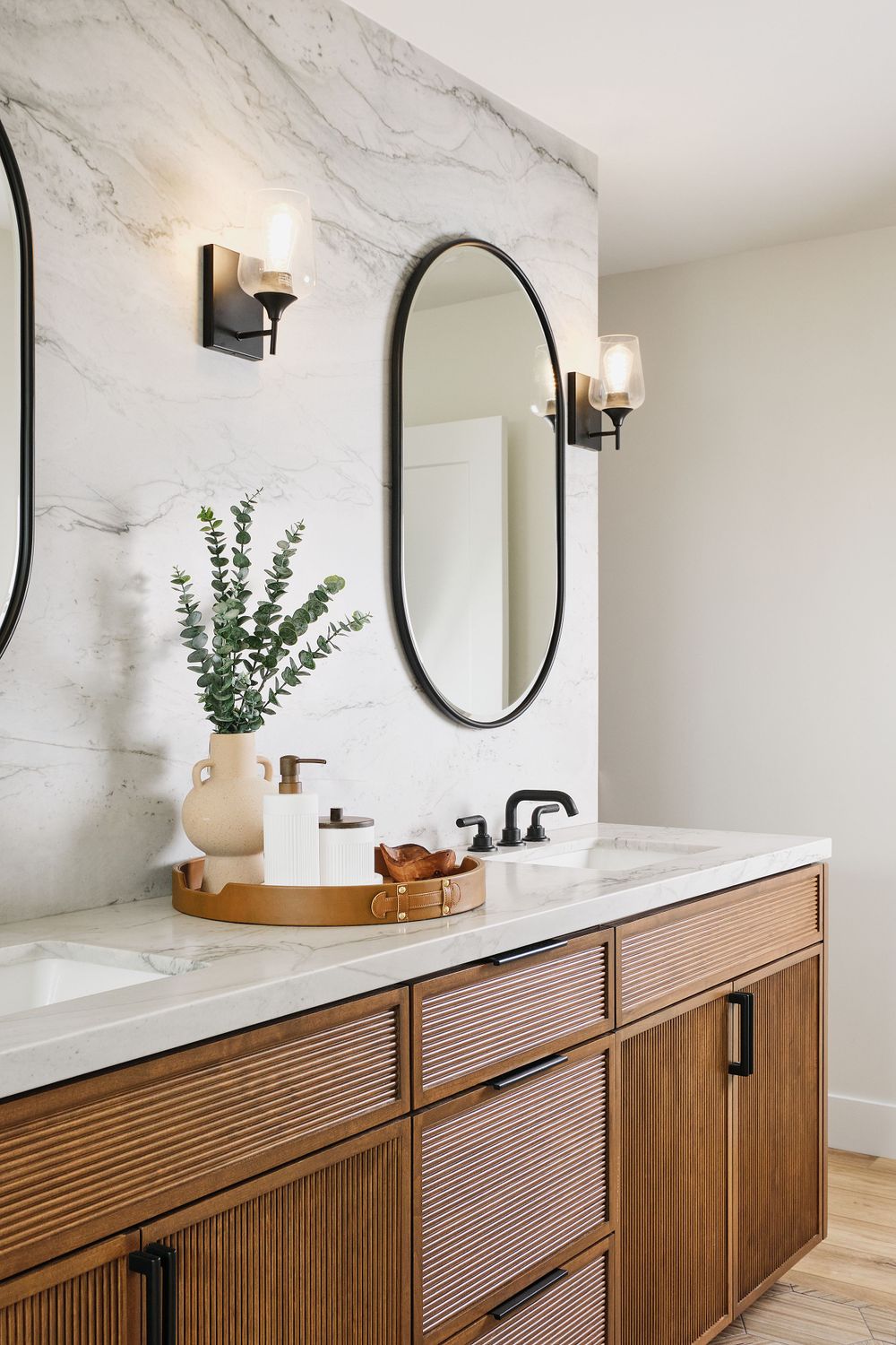 Bathroom with dual sinks, oval mirrors, and marble backsplash — modern rustic style photographed by Khoi Ly.