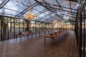 Rustic greenhouse interior set for a wedding reception with natural lighting streaming through glass panels.