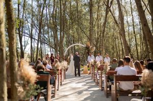 Natural forest path lined with wooden benches creates an intimate outdoor wedding ceremony space.