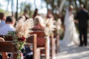 Intimate forest wedding ceremony with white and burgundy floral arrangements and natural decor.