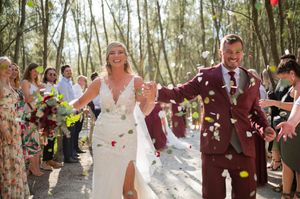A joyous wedding recessional shows celebration with confetti in a wooded outdoor setting.