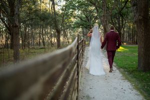 A couple walks along a wooded path during their wedding photoshoot.