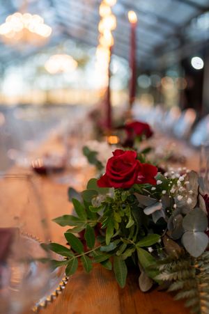 Elegant table setting with red roses and bokeh lighting at a wedding reception.