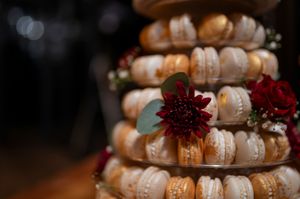 Tower of macarons decorated with burgundy flowers and greenery.