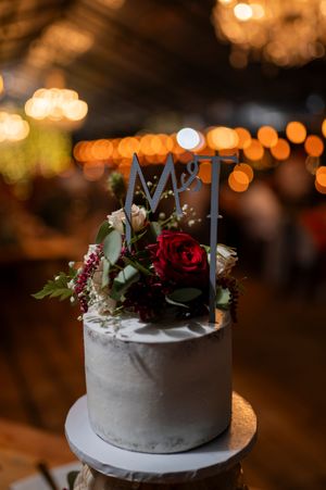 White wedding cake with floral topper and bokeh lights in background.