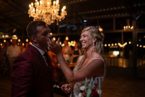 Joyful couple sharing a candid laughing moment during their wedding reception under chandeliers.