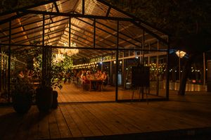 Rustic wooden wedding venue with string lights and chandeliers creating ambient evening atmosphere.
