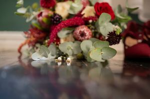 Elegant floral arrangement with red roses and greenery on a dark surface.