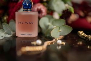 Perfume bottles arranged among flowers and soft lighting.