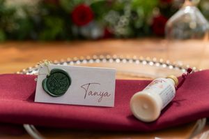 Red and white floral wedding decorations and name cards displayed on a burgundy background.