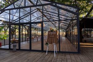 Large glass greenhouse venue with wooden floors and exposed beams in a panoramic view.