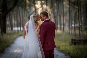 Romantic forest path portraits of newlyweds in burgundy and white attire.