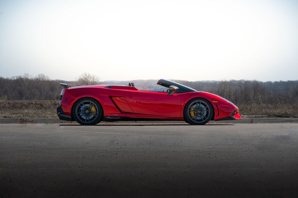 Red sports car photographed low to the ground on a scenic road.