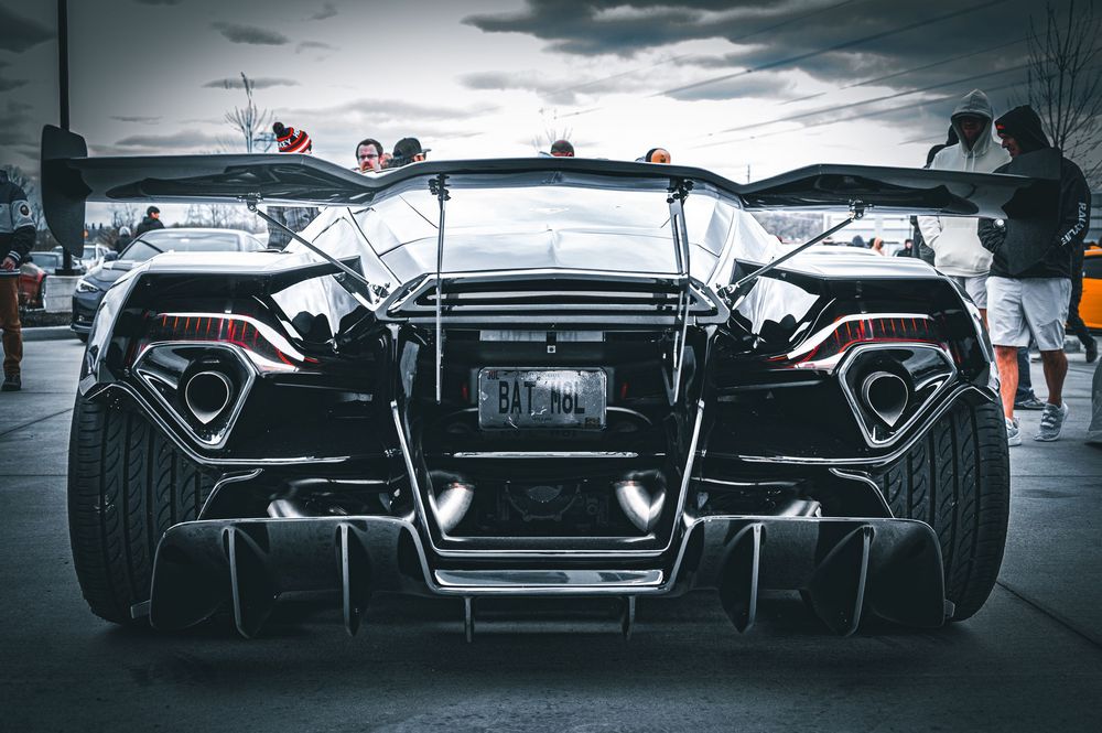 Dramatic low-angle view of supercar rear ends lined up in moody lighting.
