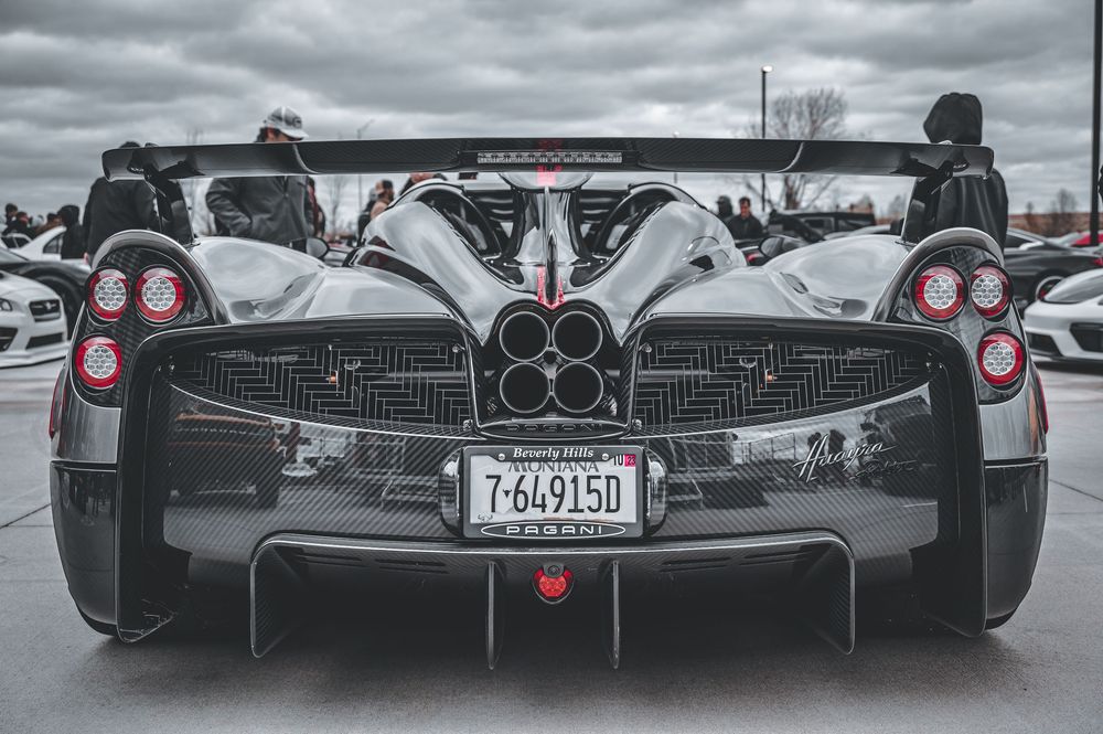 Row of exotic supercars showcasing their rear designs in dramatic lighting.