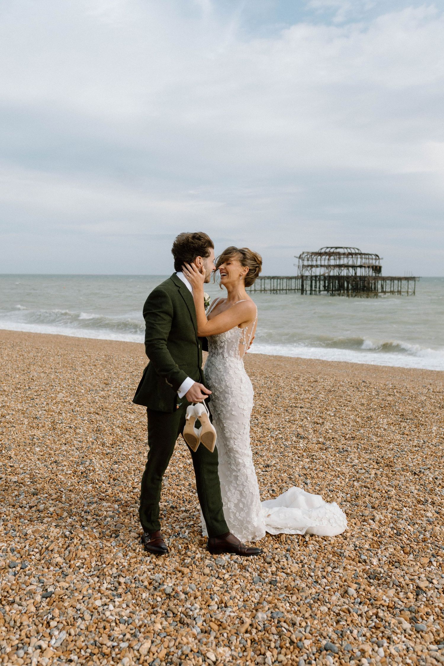 A romantic wedding moment on Brighton beach with the historic West Pier ruins visible in Brighton's West Sussex coastline.