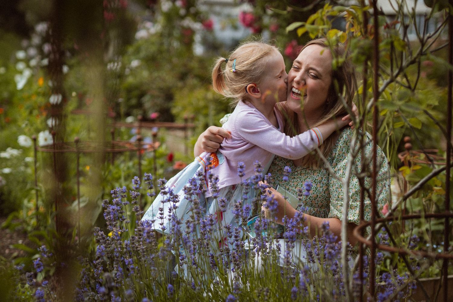 A loving embrace shared between two people amidst purple flowers in a lush summer garden.