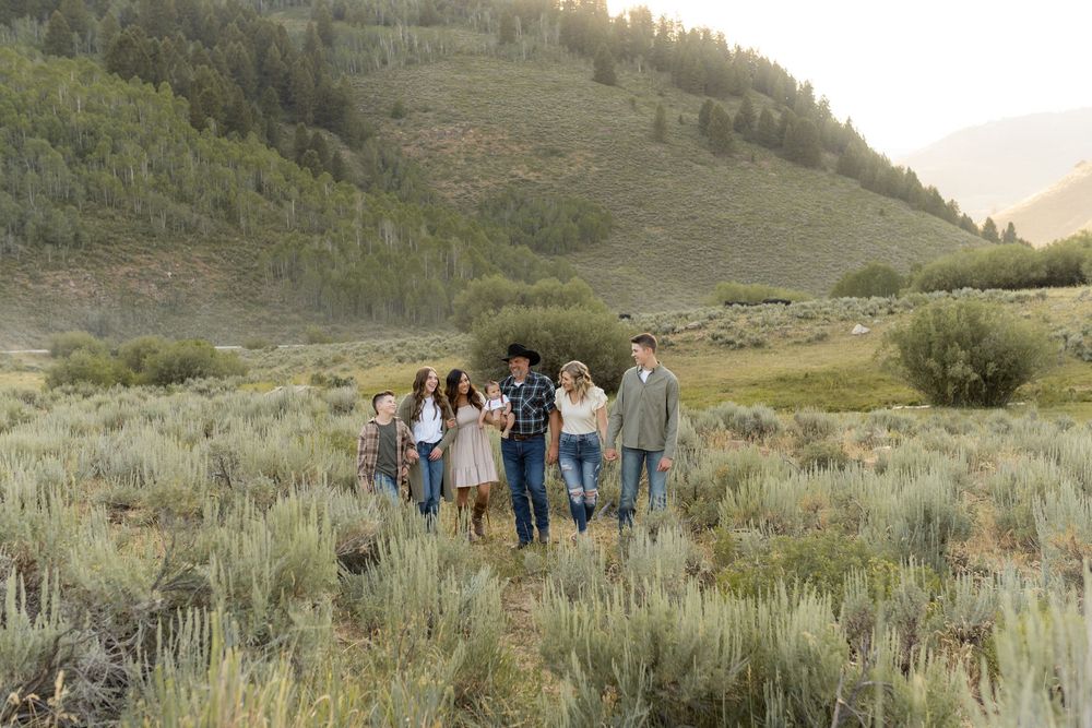 A group walks together through sage brush with mountains in the background at sunset.