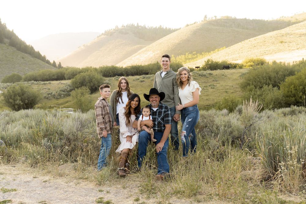 Extended family poses together on mountain trail during sunset photo session.