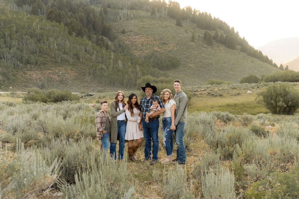 Group standing together in desert landscape with sagebrush and mountains during sunset.