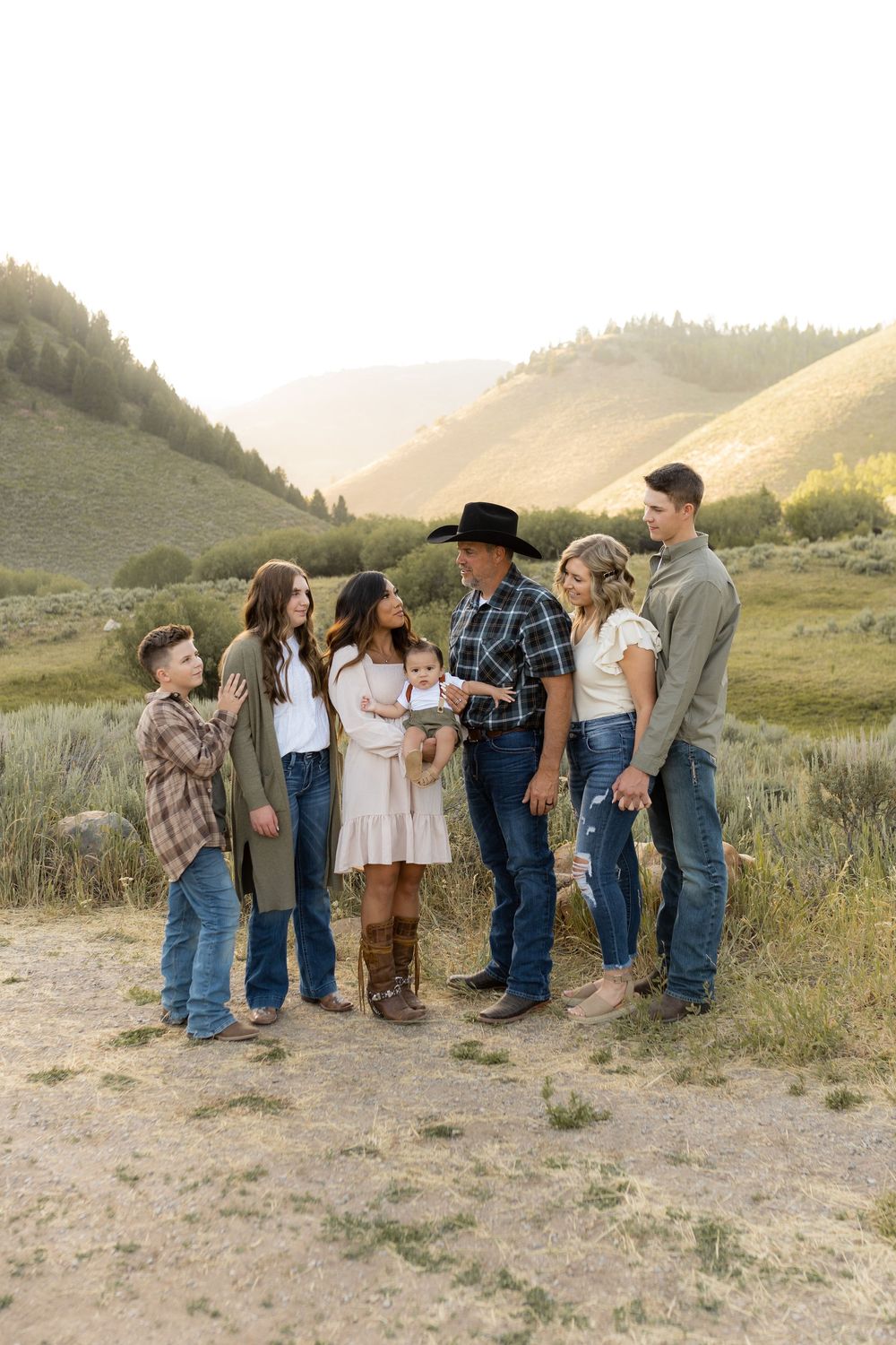 Multi-generational family gathering for portrait on mountain path at dusk.