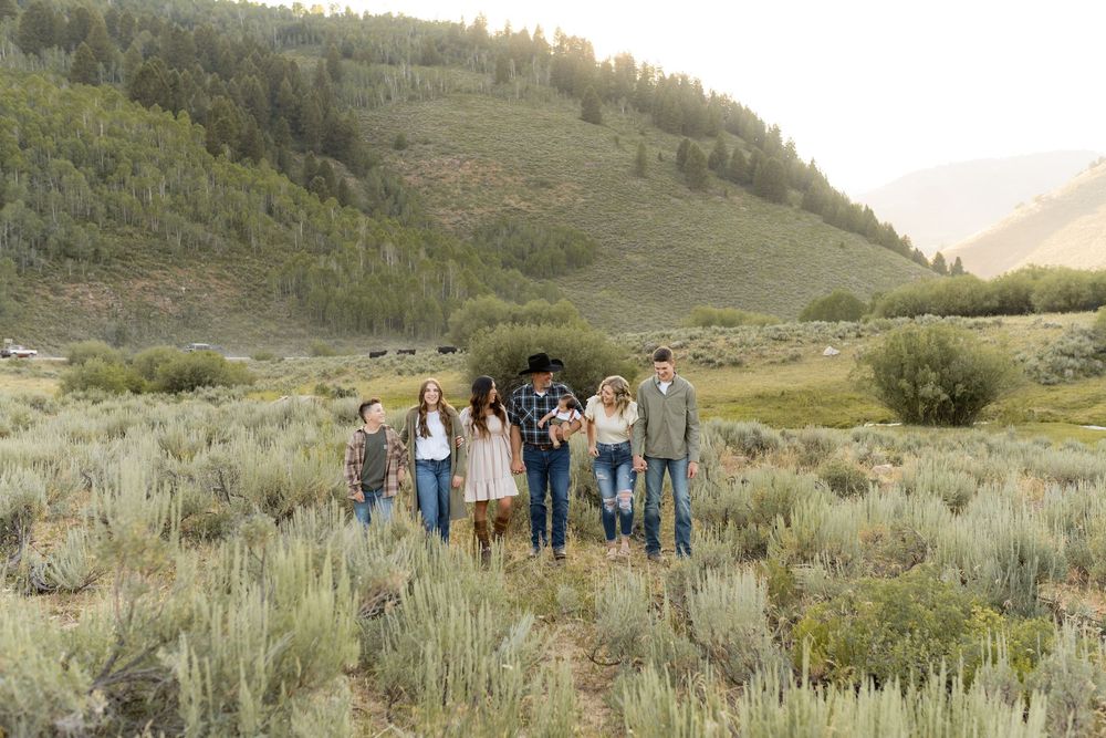 Group of people standing together in mountain valley with sagebrush and hills in background.