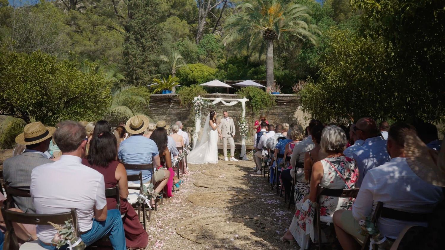 Couple exchanging vows at an outdoor wedding, with guests attentively watching in a natural setting.