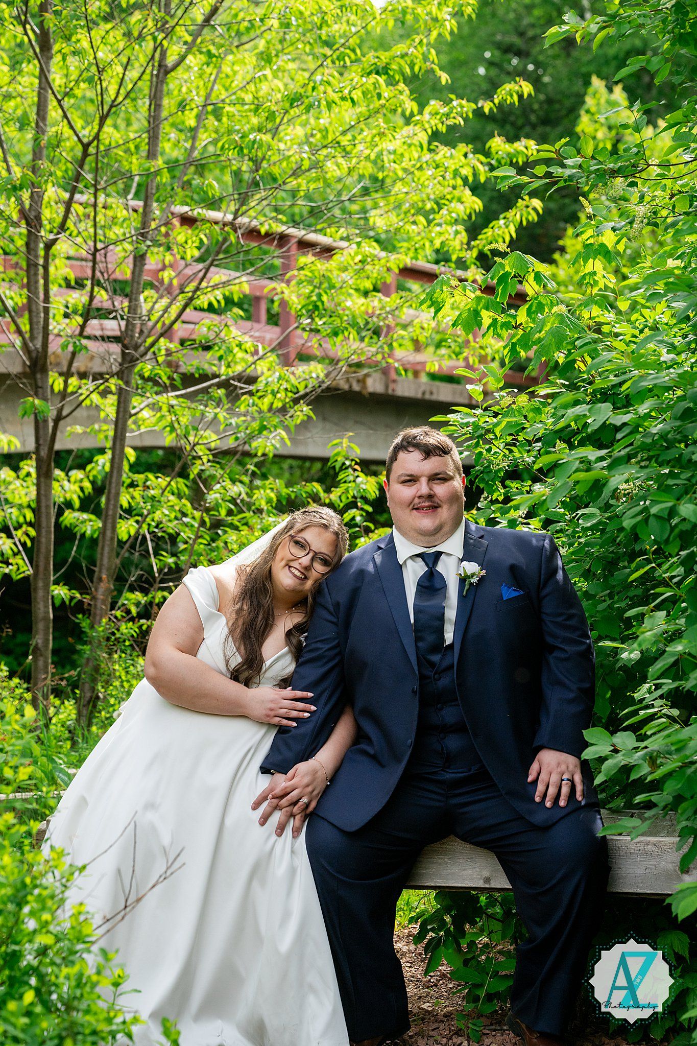 A couple shares a joyful moment together outdoors in a lush garden setting wearing wedding formal attire.