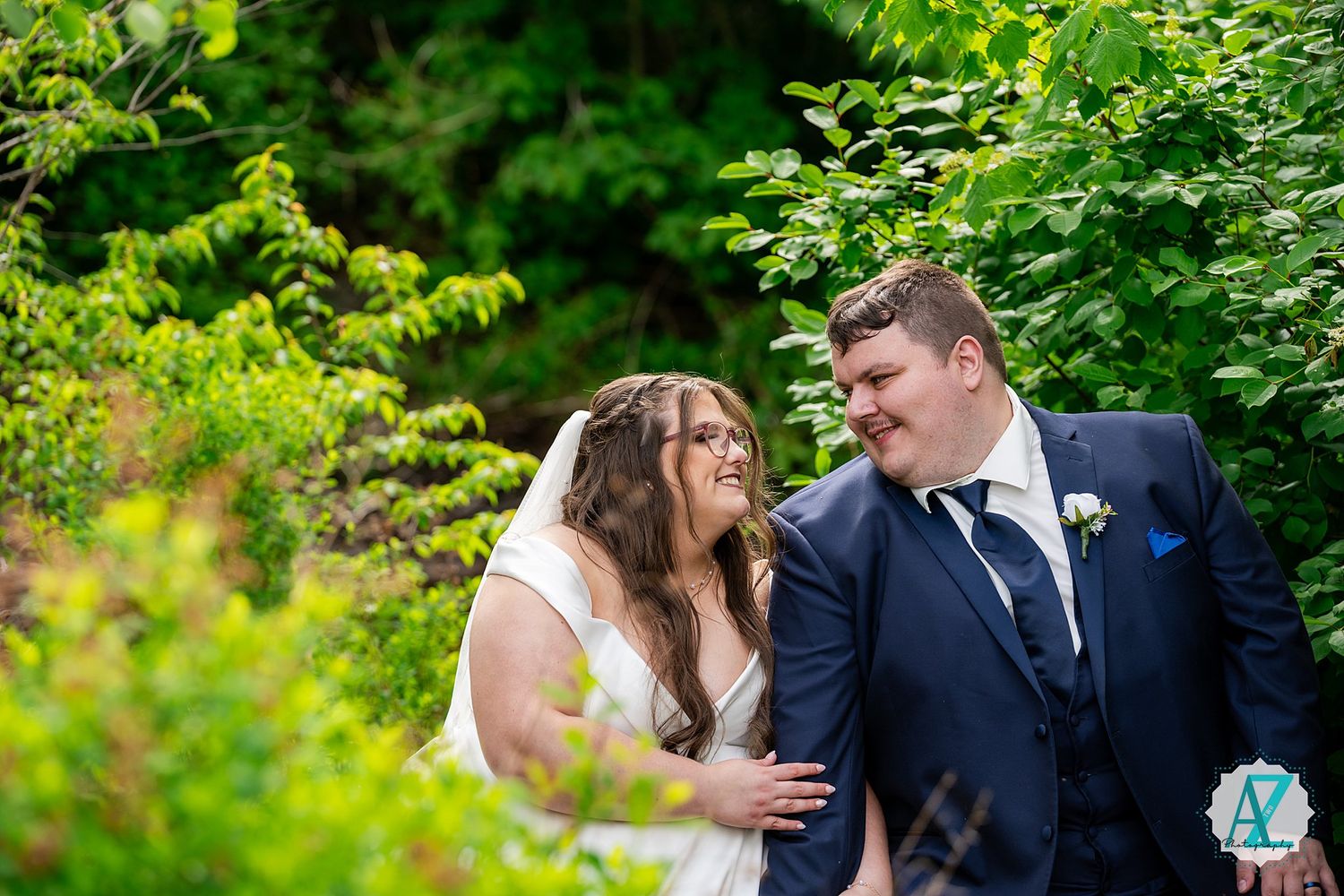 A happy wedding couple sharing an intimate moment together in a lush green garden setting.
