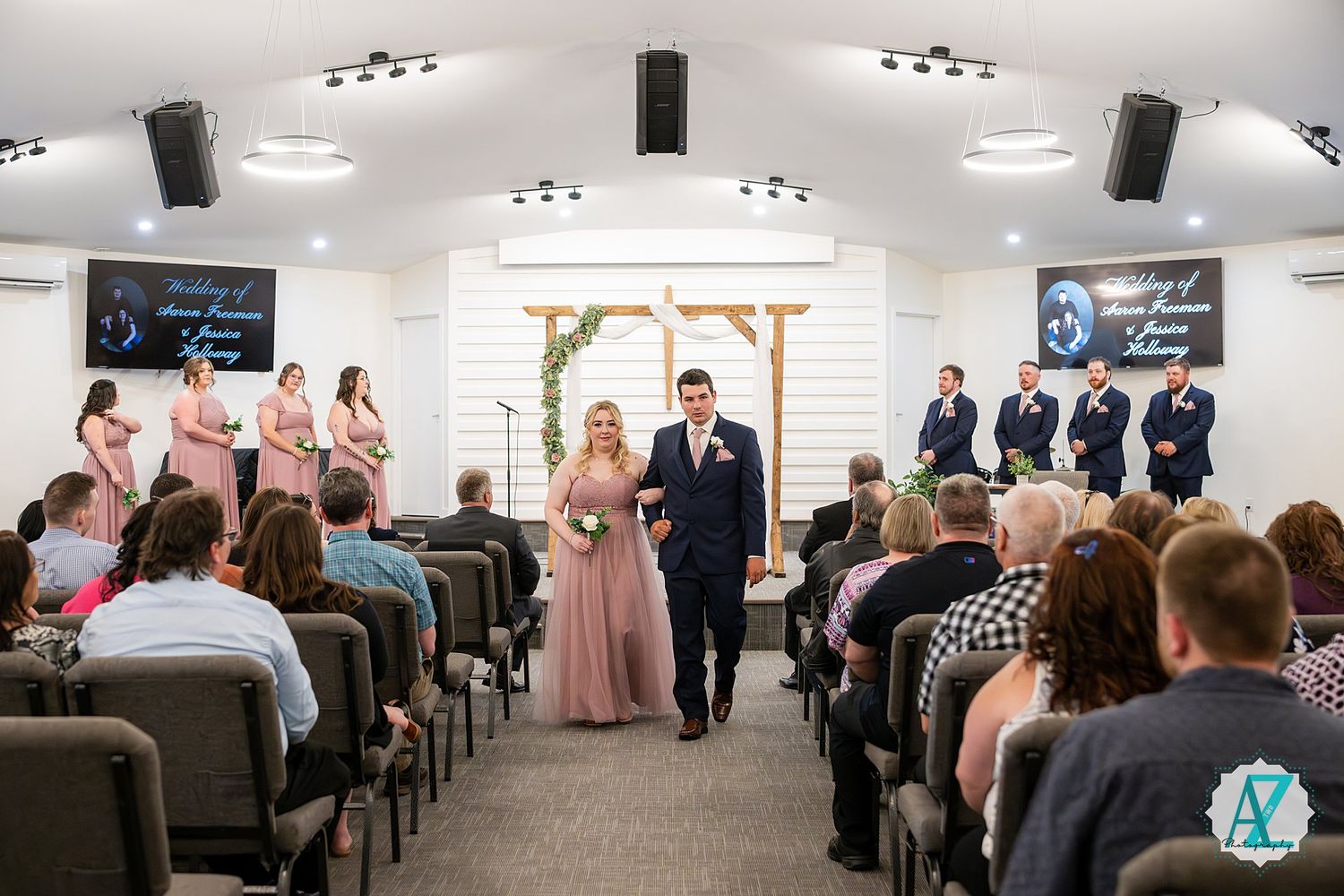 Church wedding ceremony in a modern chapel with pink bridesmaid dresses and guests seated in rows.