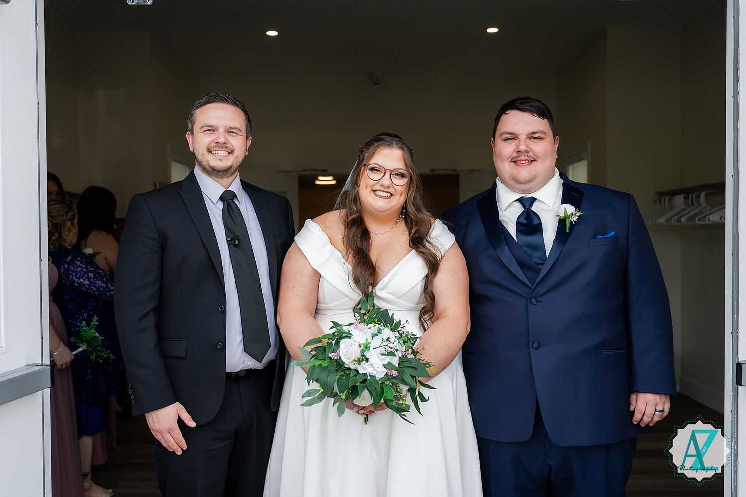 Wedding party members celebrate in formal attire while standing in a bright indoor venue.