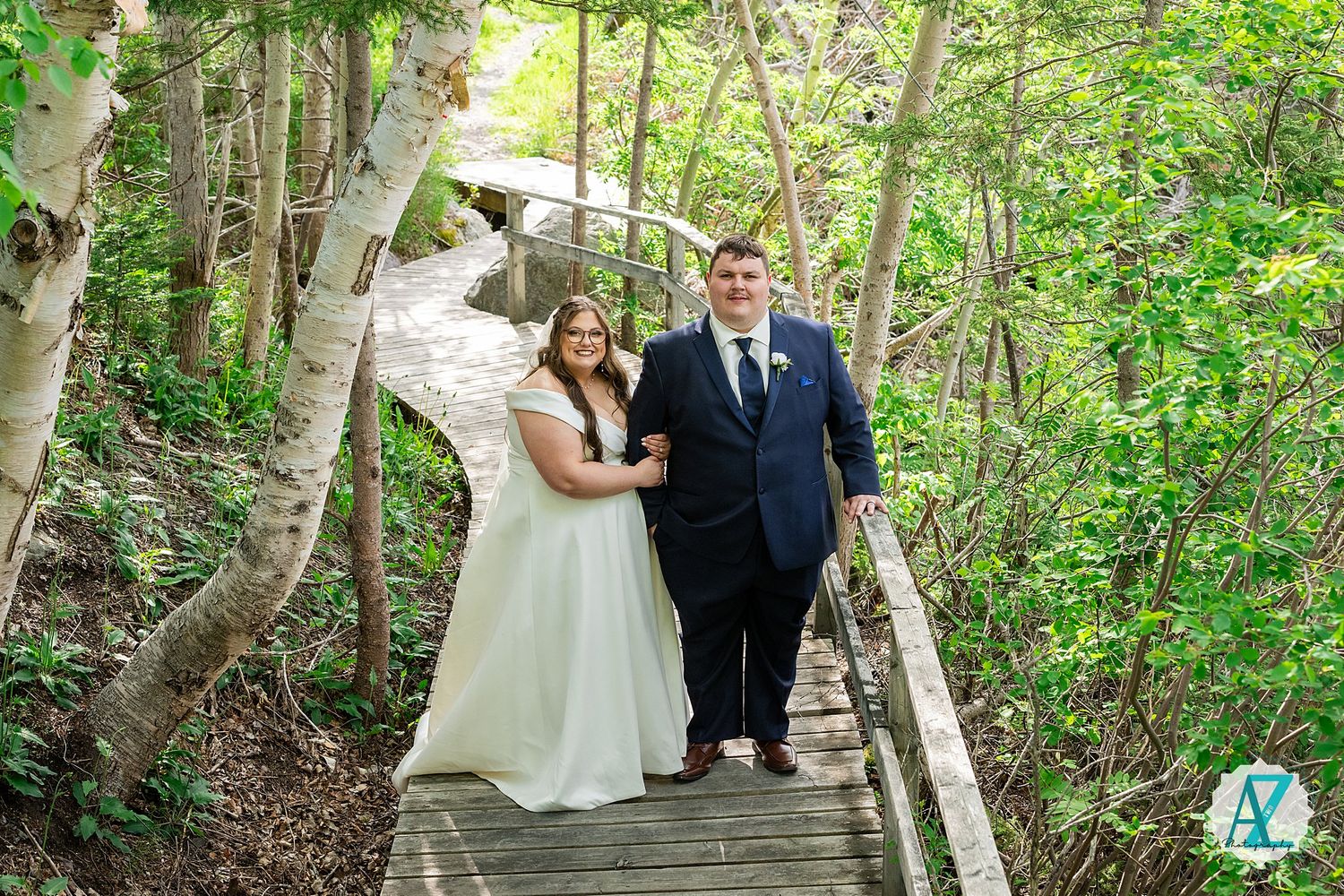 Newlywed couple poses for romantic wedding photographs in a lush green forest setting.