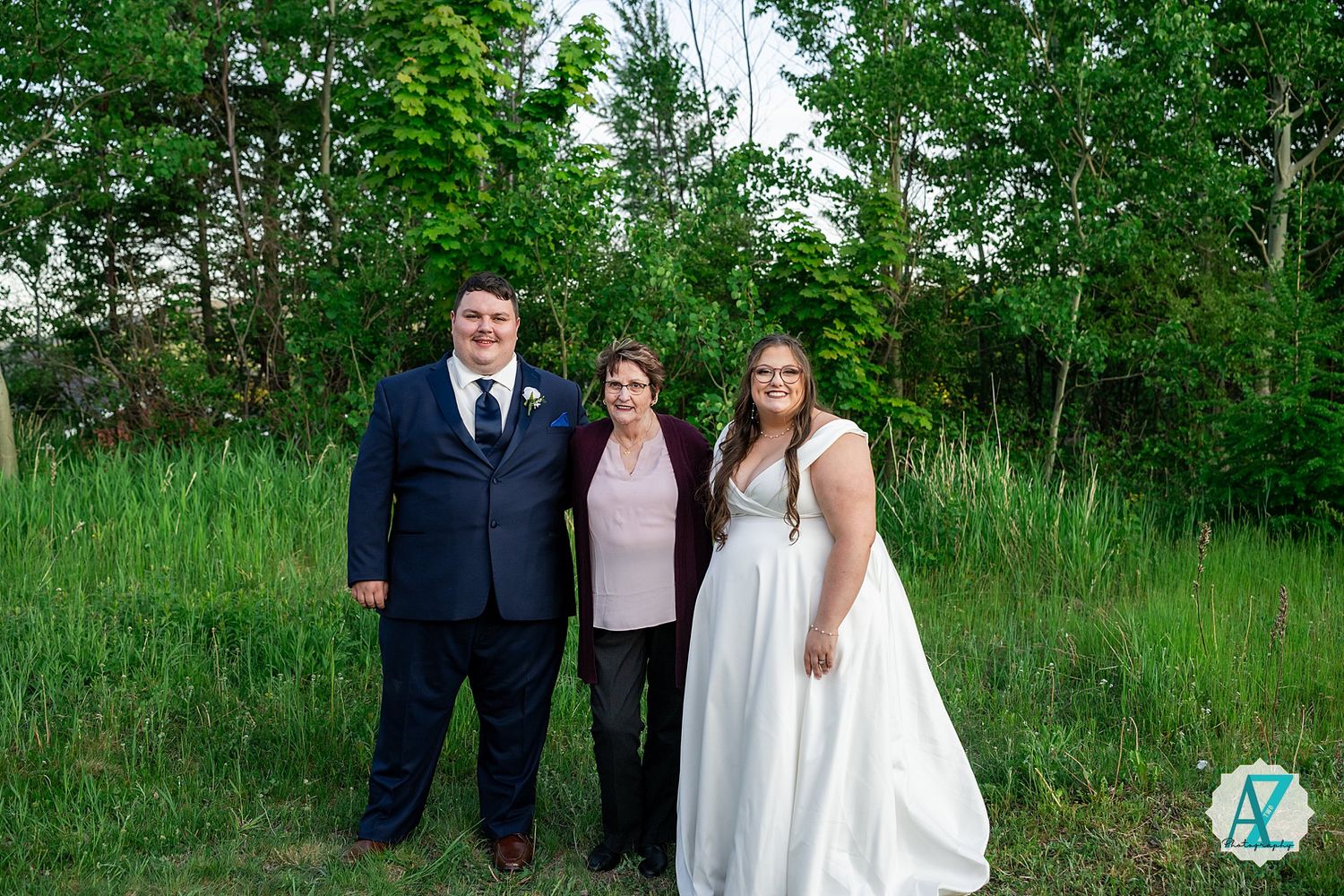 Newlywed couple stands among lush green foliage in an outdoor garden setting during their wedding photoshoot.