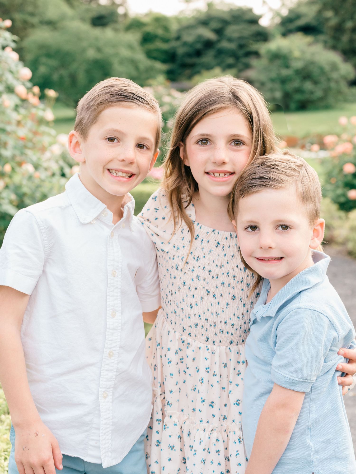 Candid moment of a 3 children from a family laughing together surrounded by blooming trees at Deep Cut Gardens.