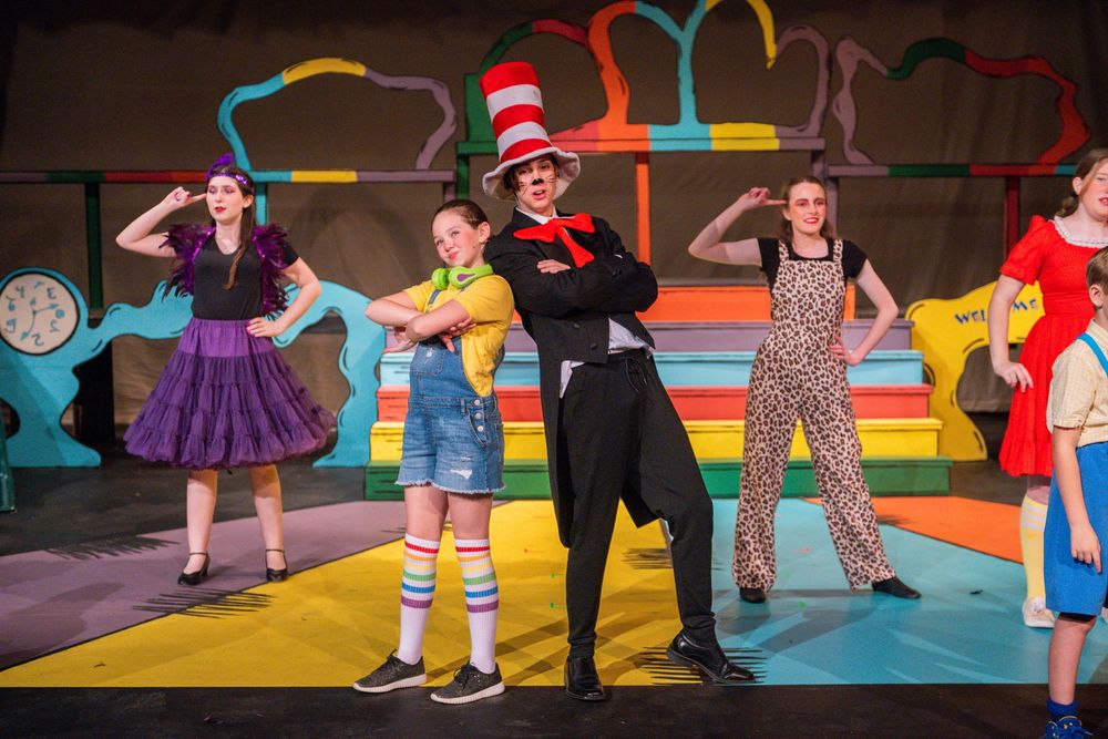 Colorful stage performance of Seussical musical with actors in vibrant costumes performing on a whimsical set.
