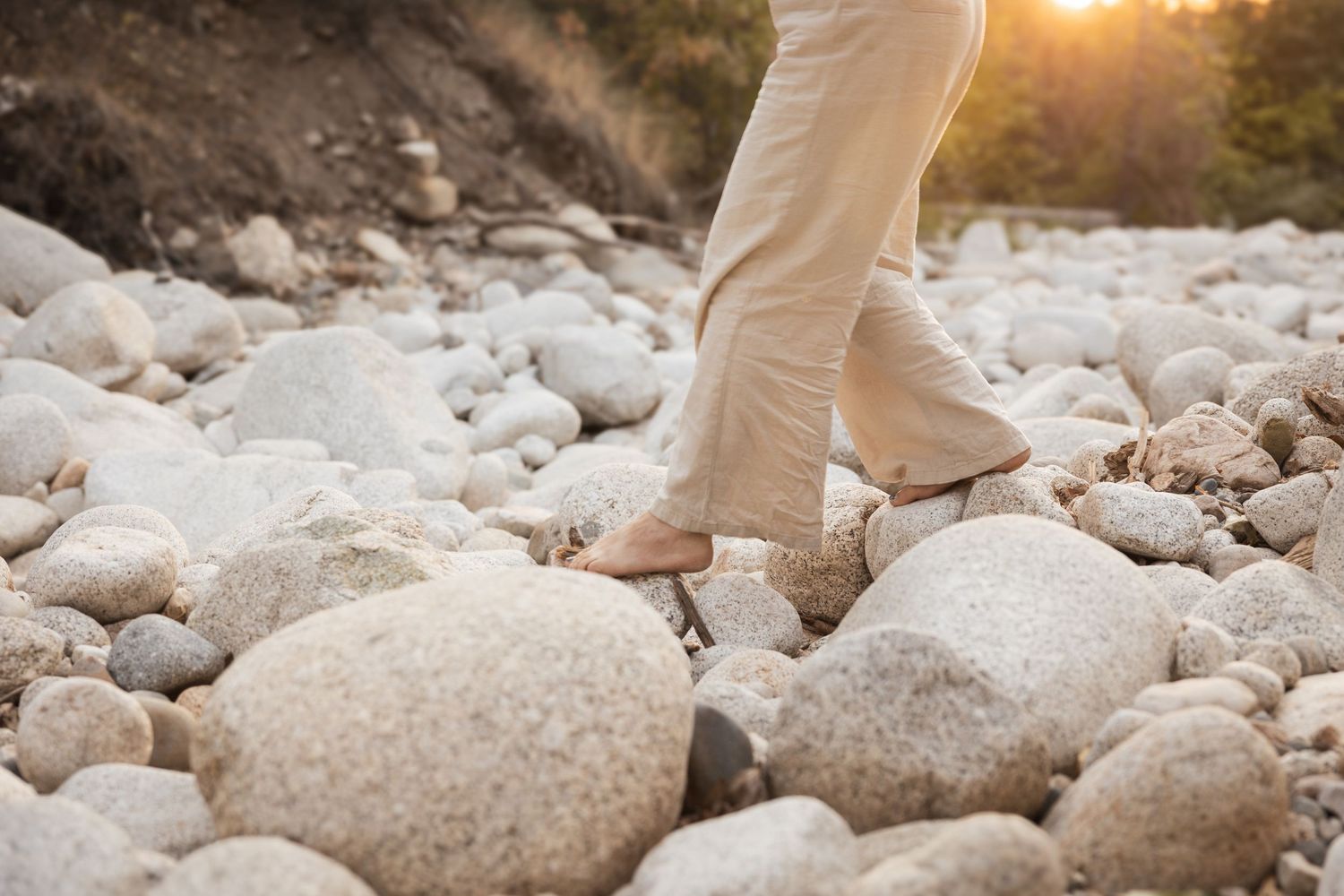 Woman walks on rocks in forest in golden sunlight for nature portraits.
