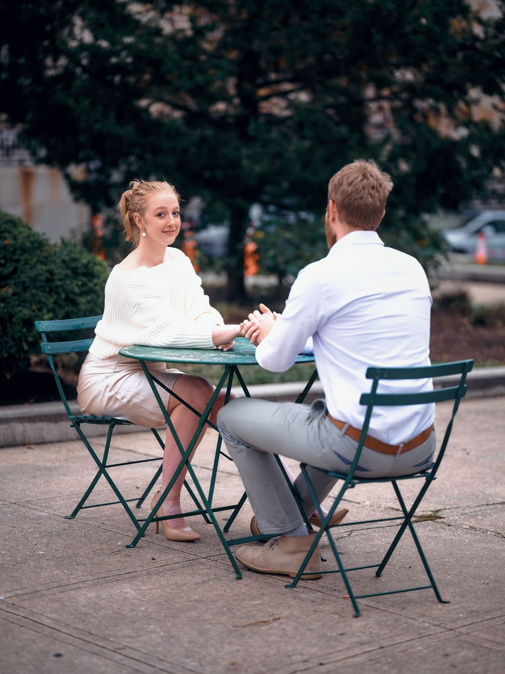 Engagement photo of couple sitting at a bistro table outside The Walters Art Museum in Mount Vernon, Baltimore.