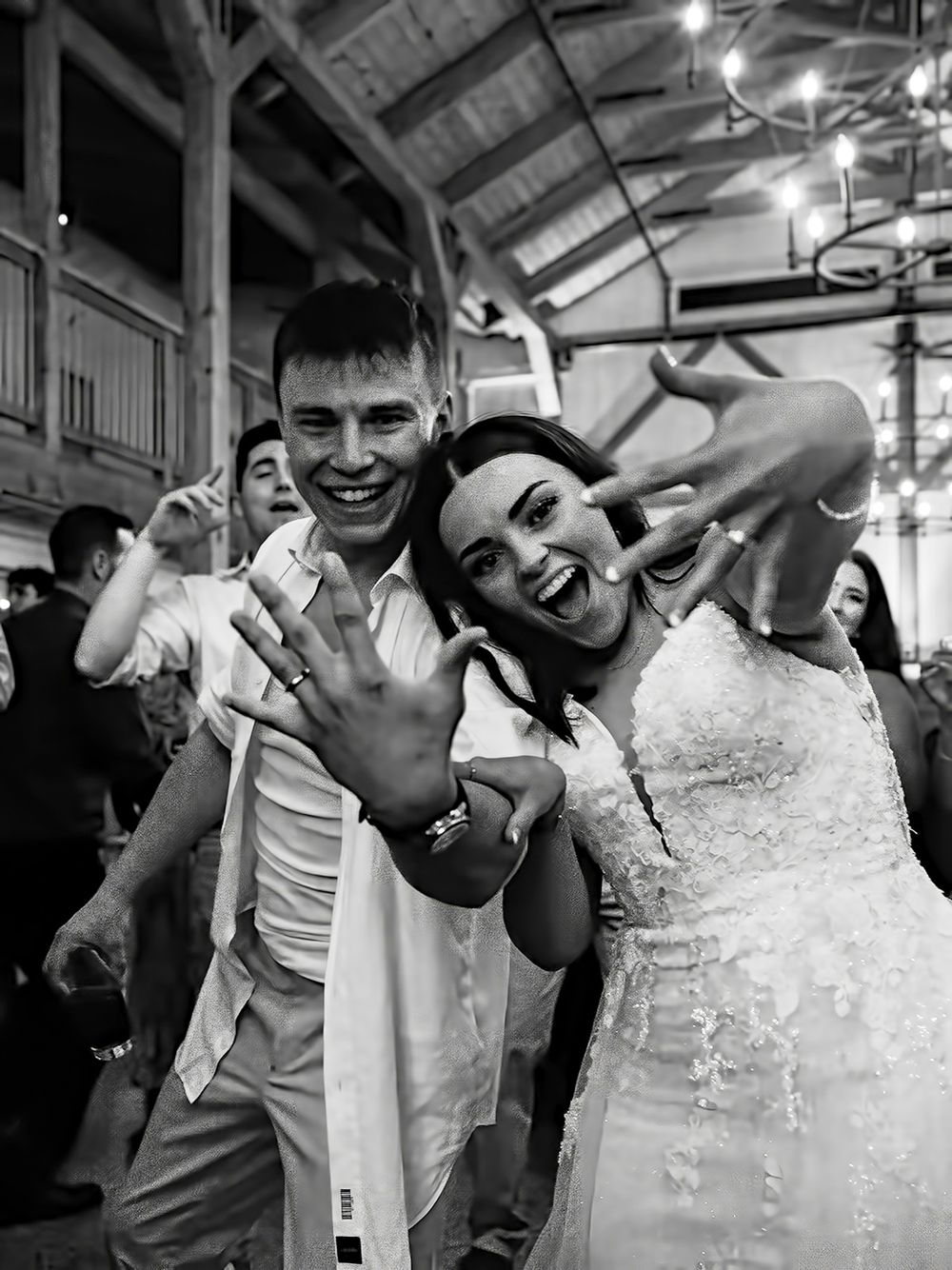 Black and white moment of couple showing off wedding rings on dancefloor at The Tannery Barn.