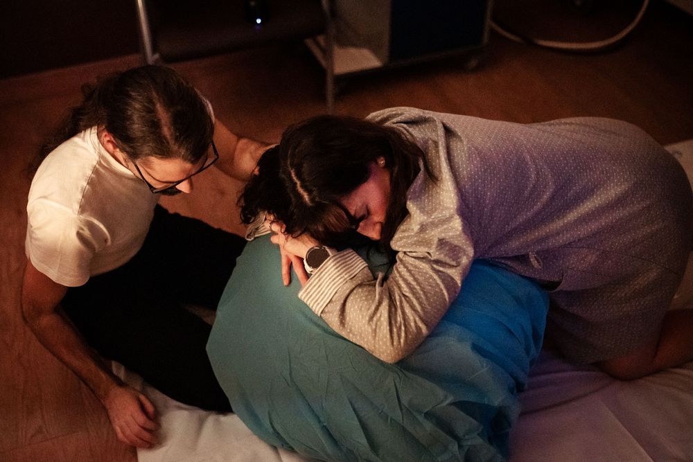 Dimly lit photographs capturing intimate moments during labor and delivery.