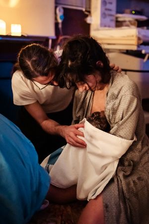 Healthcare providers assisting during childbirth in a dimly lit room.