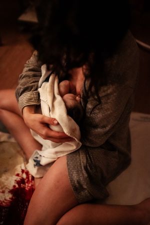 Intimate photographs capturing moments during childbirth in low light conditions.