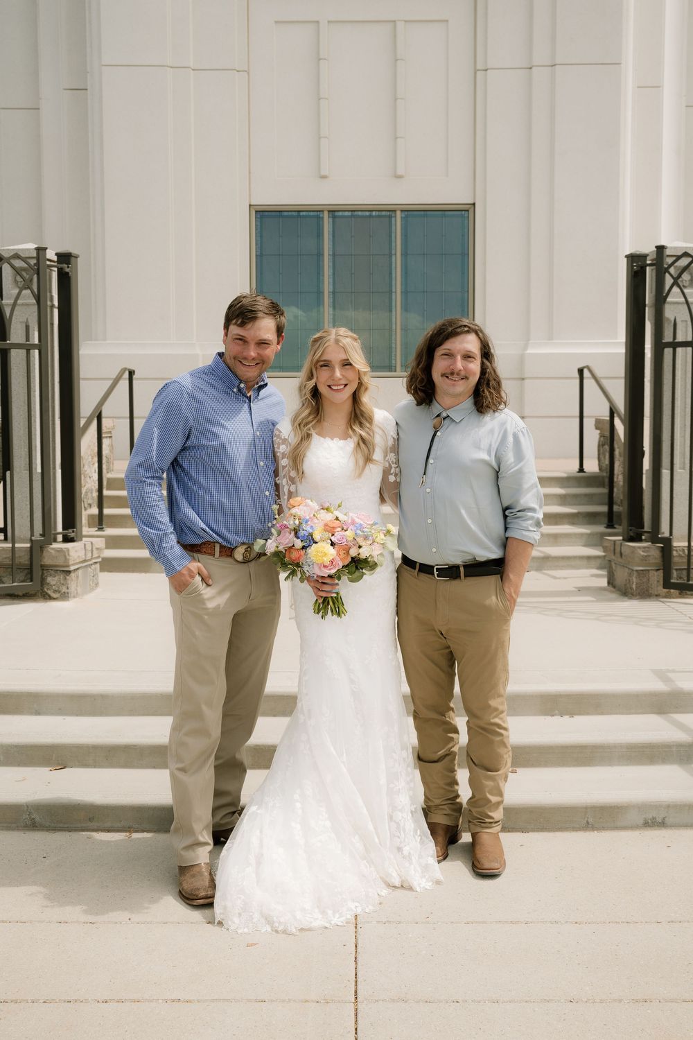 Casual portrait of wedding couple with two guests on church steps.