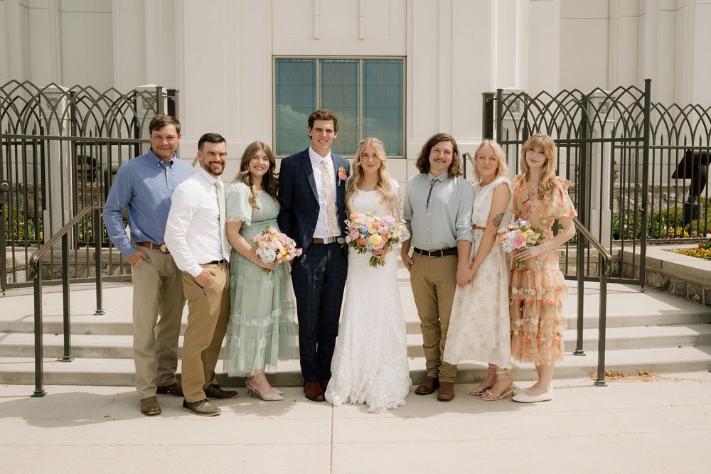 Group of formally dressed guests posing near elegant architectural columns and iron railings.