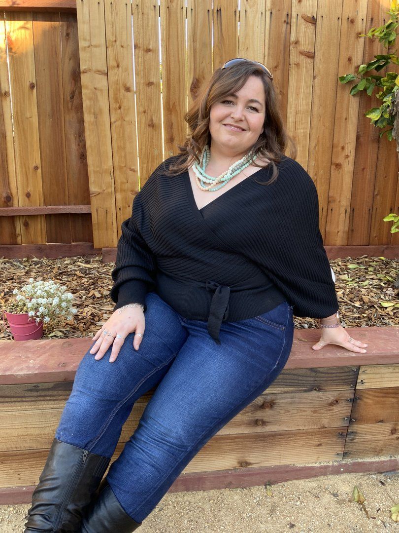 A casual outdoor portrait against a wooden fence background.
