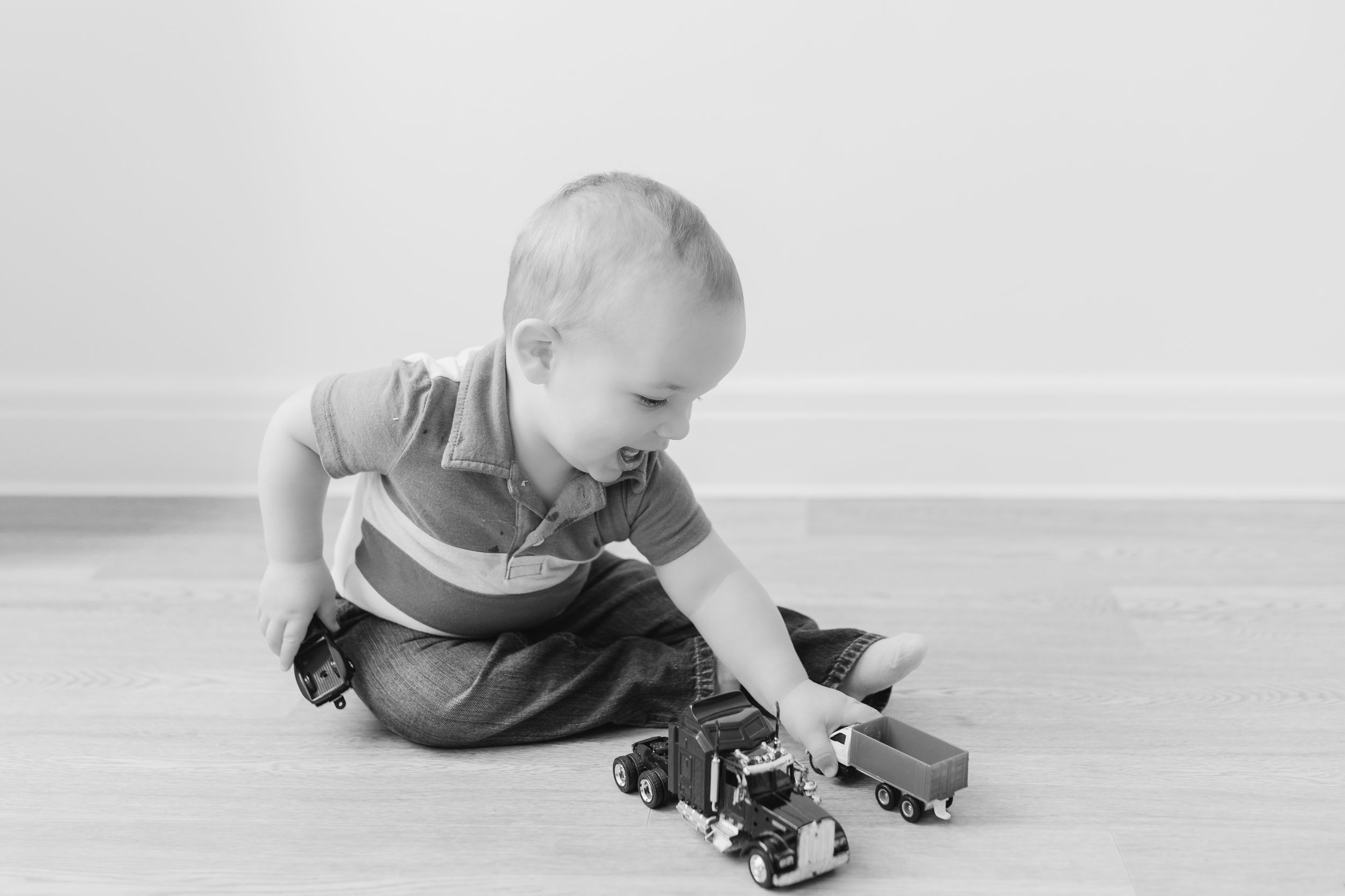 Baby crawling on hardwood floor in casual clothing.