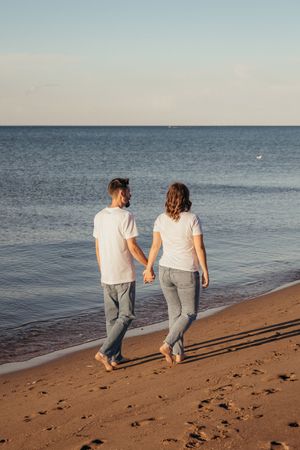 couple walk hand in hand during maternity photoshoot at sunset, Cap Pele photographer, Grand-Barachois New Brunswick, Cape Caisse