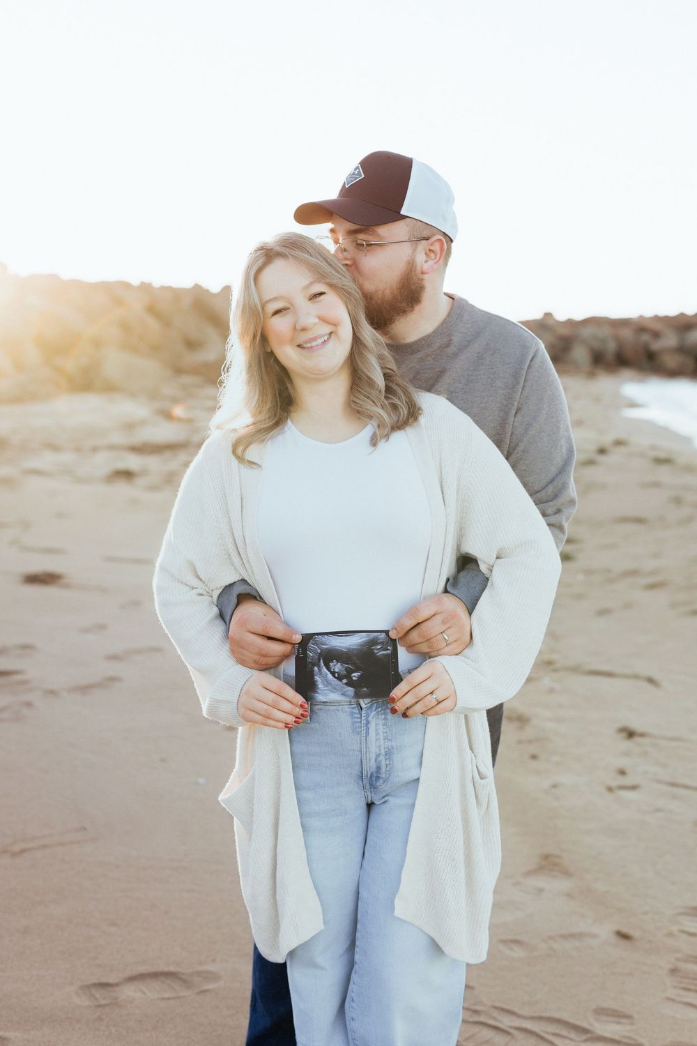 Couple embrace at sunset romantic photoshoot maternity photos at Sandy Beach, Cap Pele photographer, Aboiteau beach photos while on vacation